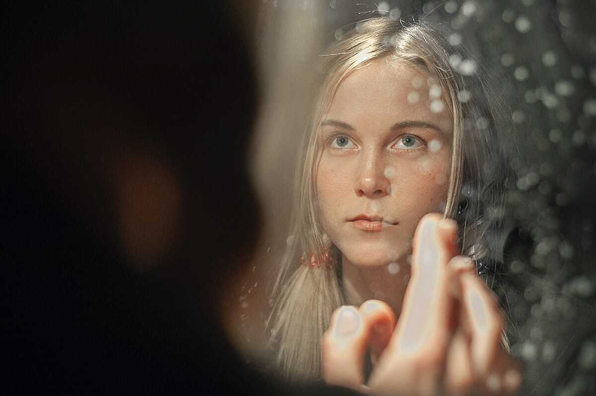 Girl looking in mirror to determine is she is ugly or beautiful.